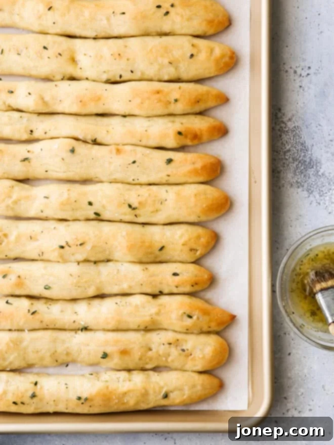 Freshly baked no-knead breadsticks glistening with garlic herb butter and coarse salt
