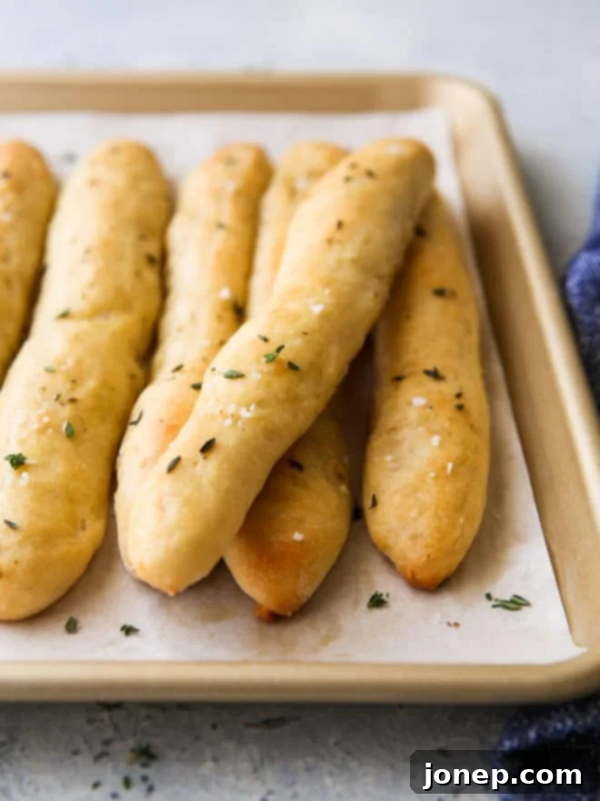 Close-up view of a baked no-knead breadstick, showing soft interior and garlic herb butter