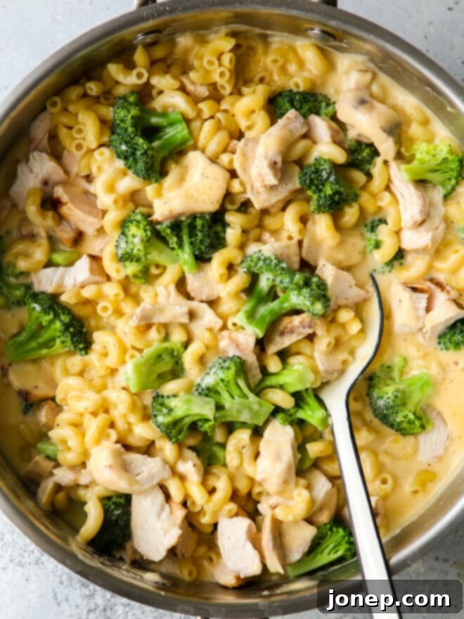 stirring chicken broccoli macaroni and cheese with a large spoon