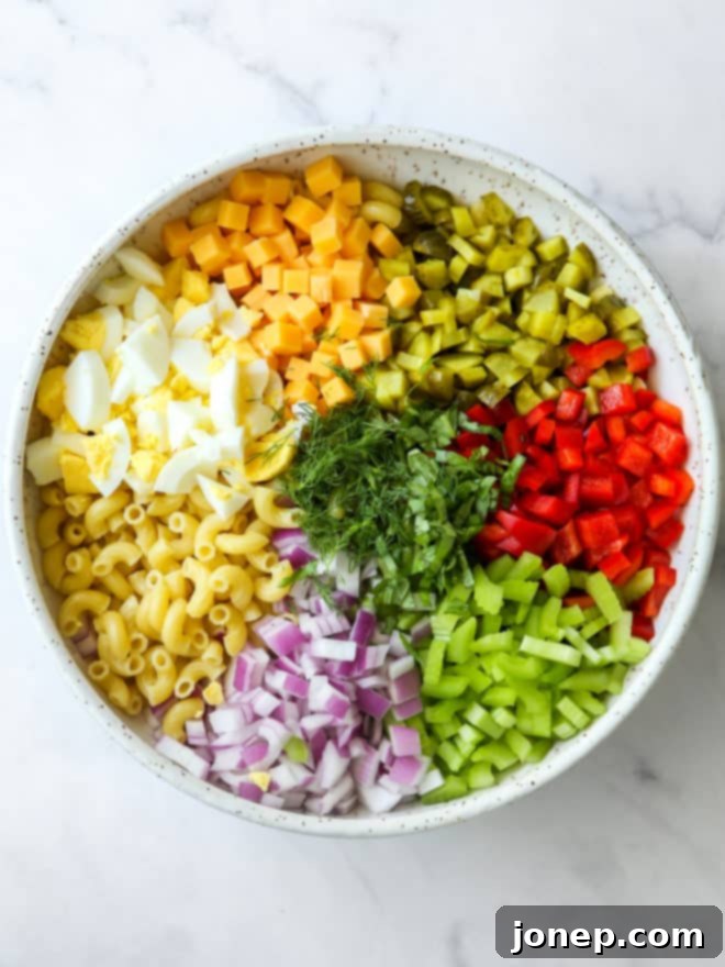 Creamy Classic Macaroni Salad 4 All ingredients for homemade macaroni salad, including pasta, fresh vegetables, and hard-boiled eggs, ready to be mixed in a large bowl.