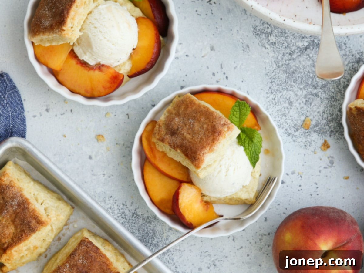 Several assembled peach shortcakes in individual bowls, featuring halved biscuits, juicy peaches, and scoops of ice cream.