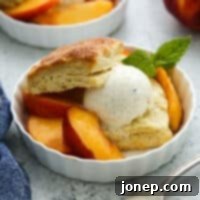Summer Peach Cream Delights 9 A close-up view of a peach shortcake with a fork, emphasizing the layers of biscuit, peaches, and melting ice cream.