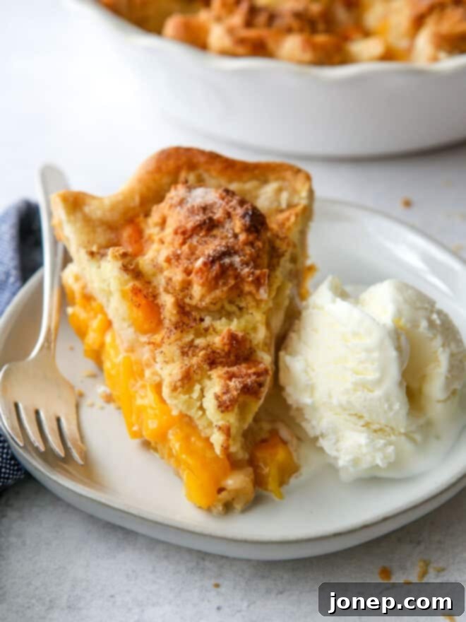 slice of peach cobbler pie on a plate with a scoop of melting vanilla ice cream