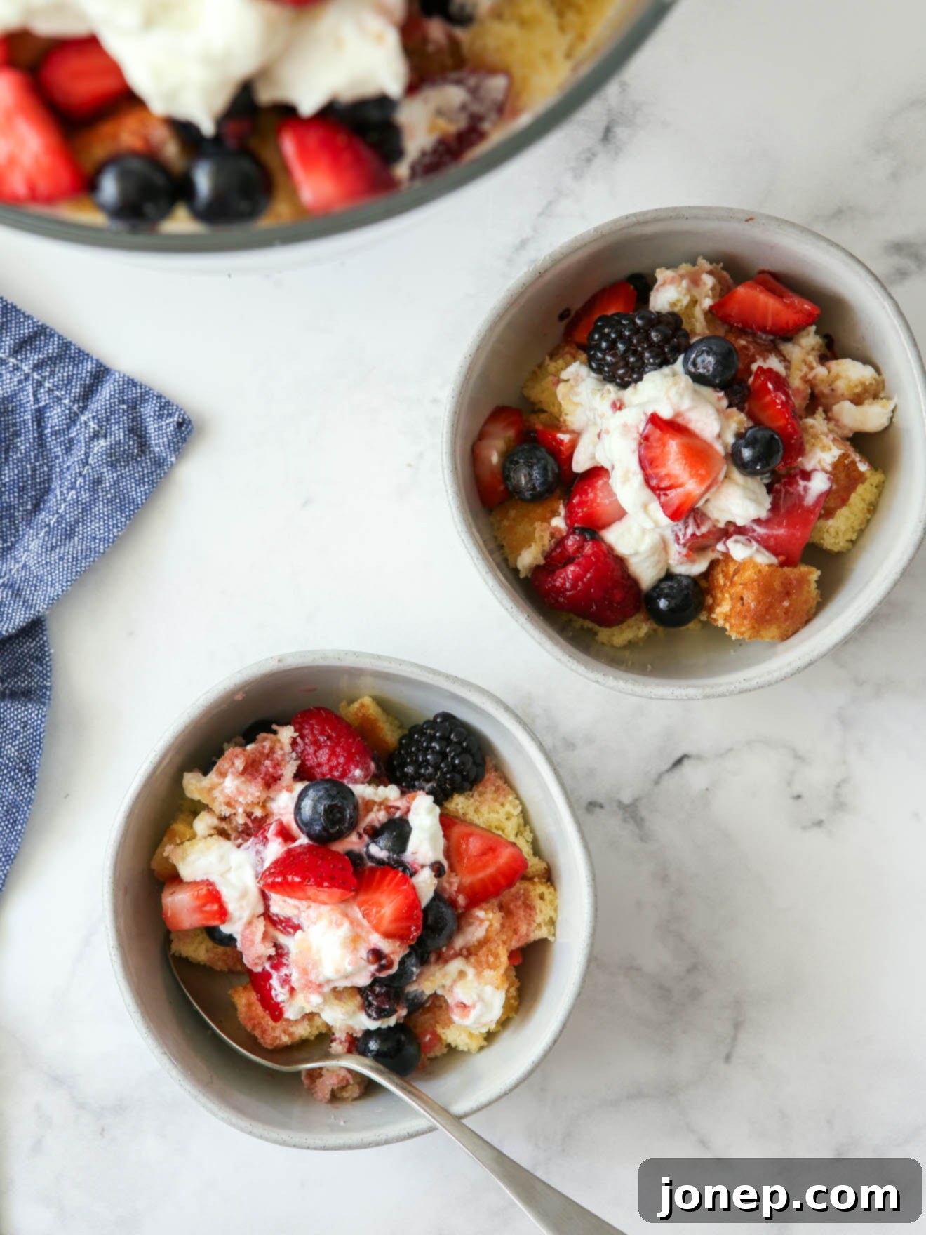 Layers of Summer Berry Bliss 10 Individual servings of berry trifle in small bowls, garnished with fresh berries.