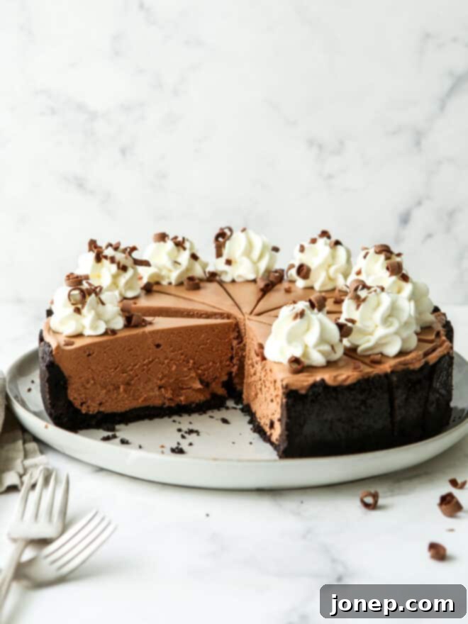 Effortless Chocolate Cheesecake Bliss 2 Side view of a tall, decadent no-bake chocolate cheesecake with whipped cream and chocolate shavings.