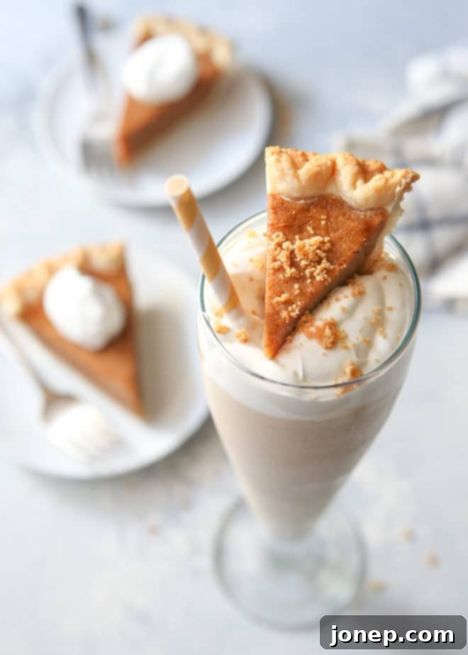 Pumpkin pie milkshake with real pumpkin pie! A creamy, golden drink topped with whipped cream and a sprinkle of cinnamon, served in a tall glass beside a piece of pumpkin pie.