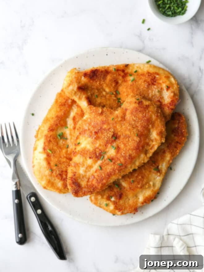 Crispy Baked Chicken 2 oven fried chicken piled on a plate with chives