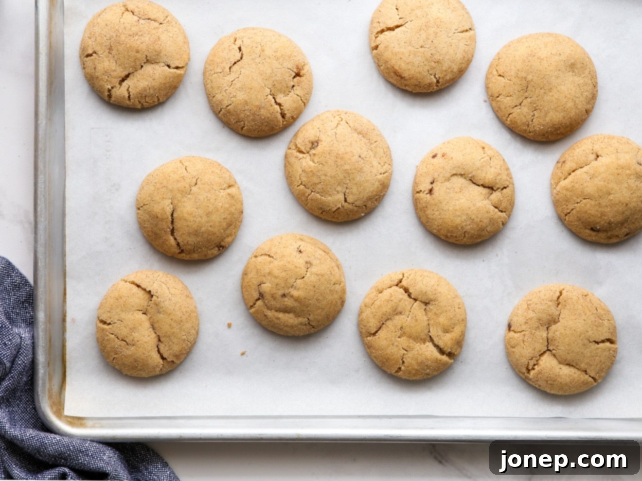 Caramelized Snickerdoodles 6 Freshly baked brown butter snickerdoodles cooling on a parchment-lined cookie sheet