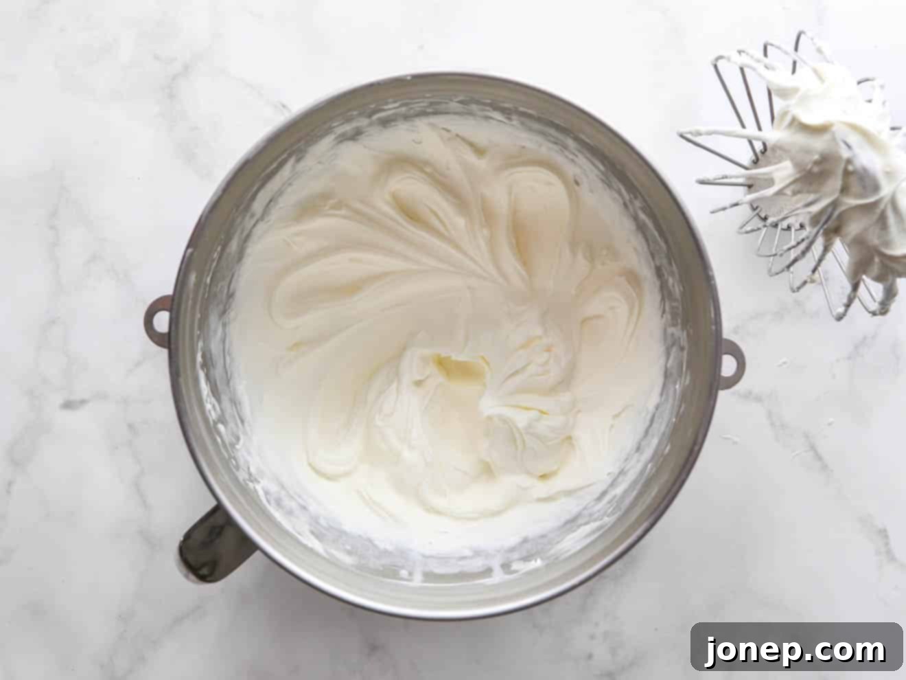 whipped chantilly frosting in a mixing bowl, showcasing its light and airy texture