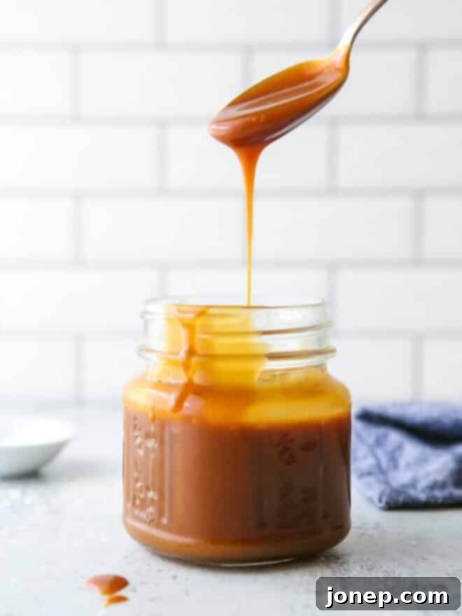 Perfect Homemade Caramel 2 pouring a spoonful of homemade caramel sauce into a jar