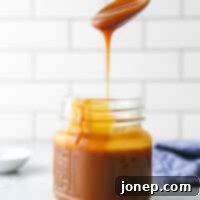 Perfect Homemade Caramel 12 pouring a spoonful of homemade caramel sauce into a jar