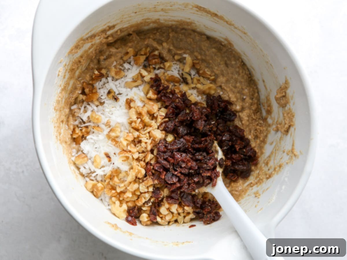 Mixing bran muffin batter in a large white bowl with a spatula, showing the wet and dry ingredients just combined