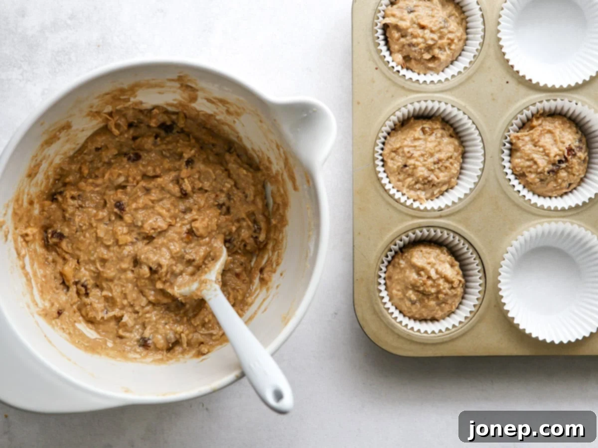 Scooping bran muffin batter into a muffin pan lined with paper liners, ready for baking
