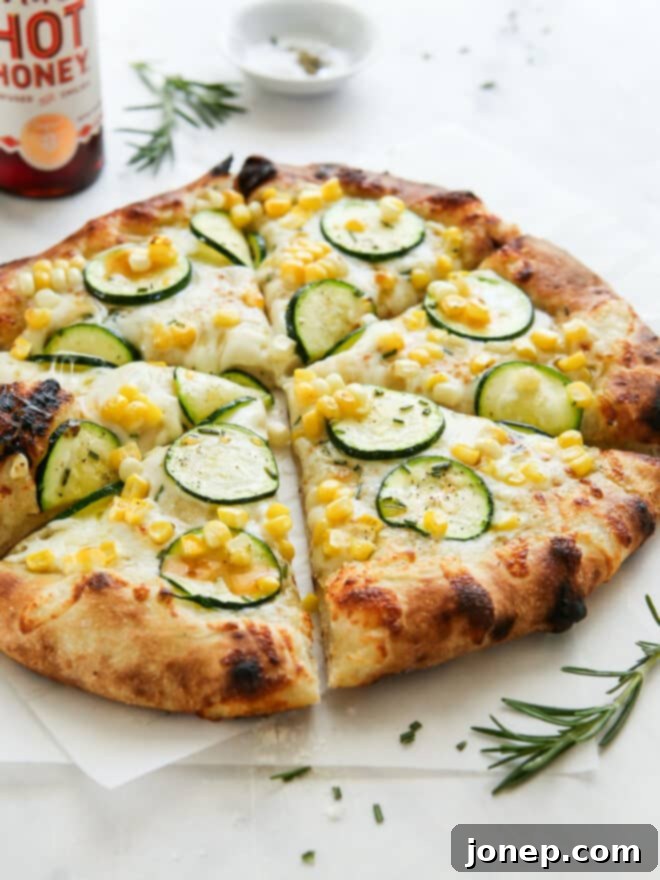 Sweet Corn and Zucchini Pizza 3 sliced zucchini corn pizza with hot honey bottle in the background