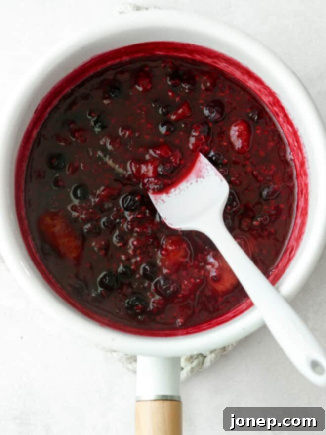 Sweet Berry Medley 6 Finished berry compote, showcasing its rich texture and color, in a saucepan with a spatula.
