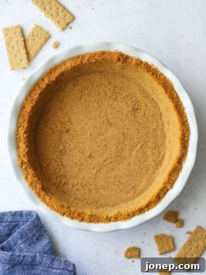 Beautifully golden-brown baked graham cracker pie crust in a pie plate, ready for filling.