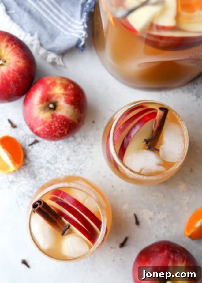 A glass of Spiced Apple Cider Sangria garnished with an apple slice and orange.