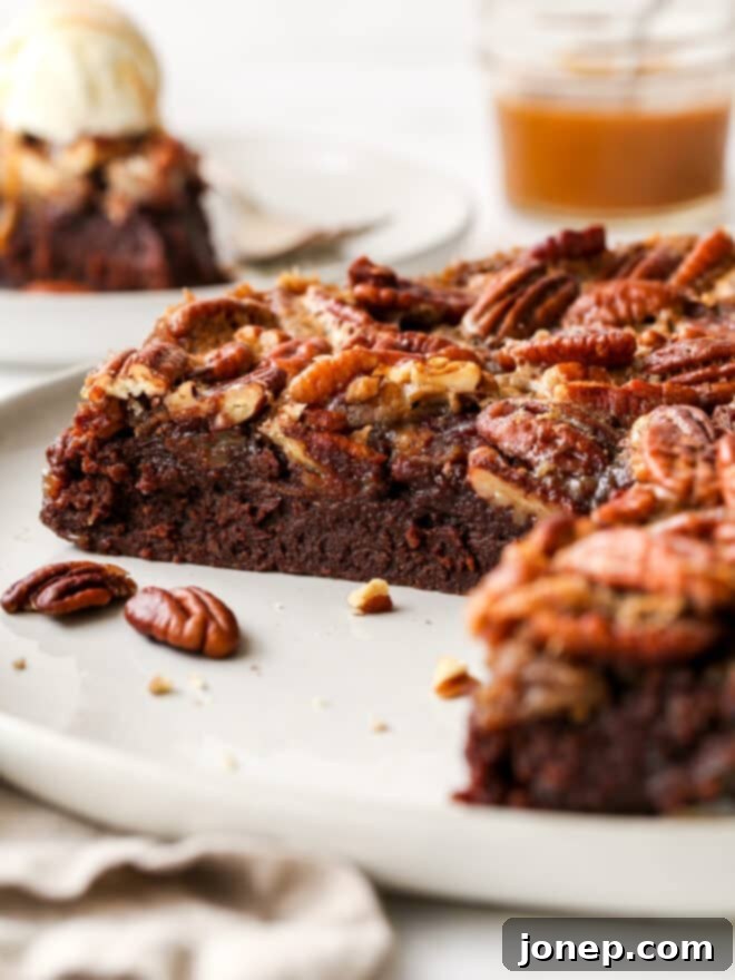 Close-up of a freshly baked pecan pie brownie, showcasing its fudgy interior and glossy pecan topping.