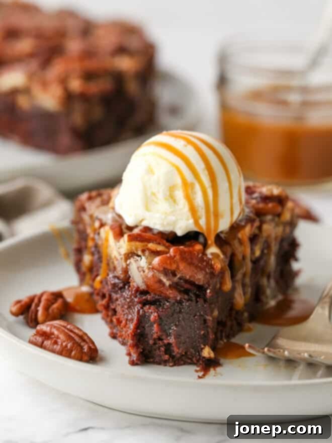 A slice of pecan pie brownie with a bite taken out, topped with melting vanilla ice cream and a caramel drizzle, on a white plate.