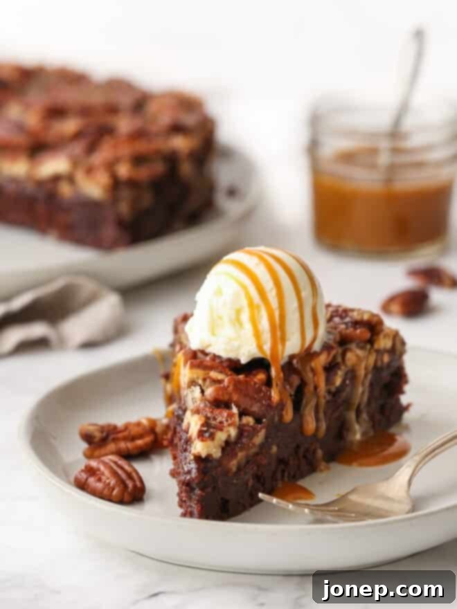 A perfectly sliced pecan pie brownie topped with a scoop of vanilla ice cream and a luxurious caramel drizzle.