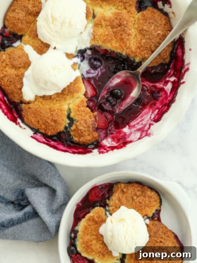Rustic Berry Cobbler 3 Close-up view of a spoon scooping out a generous portion of warm, bubbly berry cobbler from a baking dish, showcasing the rich fruit filling and golden topping.