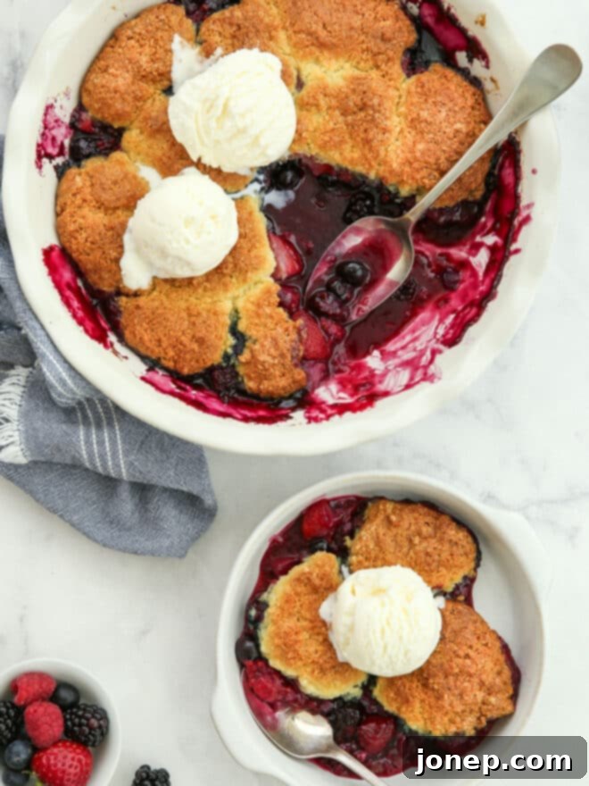 Rustic Berry Cobbler 7 A hand holding a scoop of warm berry cobbler, topped with a melting scoop of vanilla ice cream, about to be placed into a bowl.