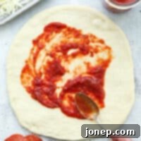 spreading pizza sauce on dough