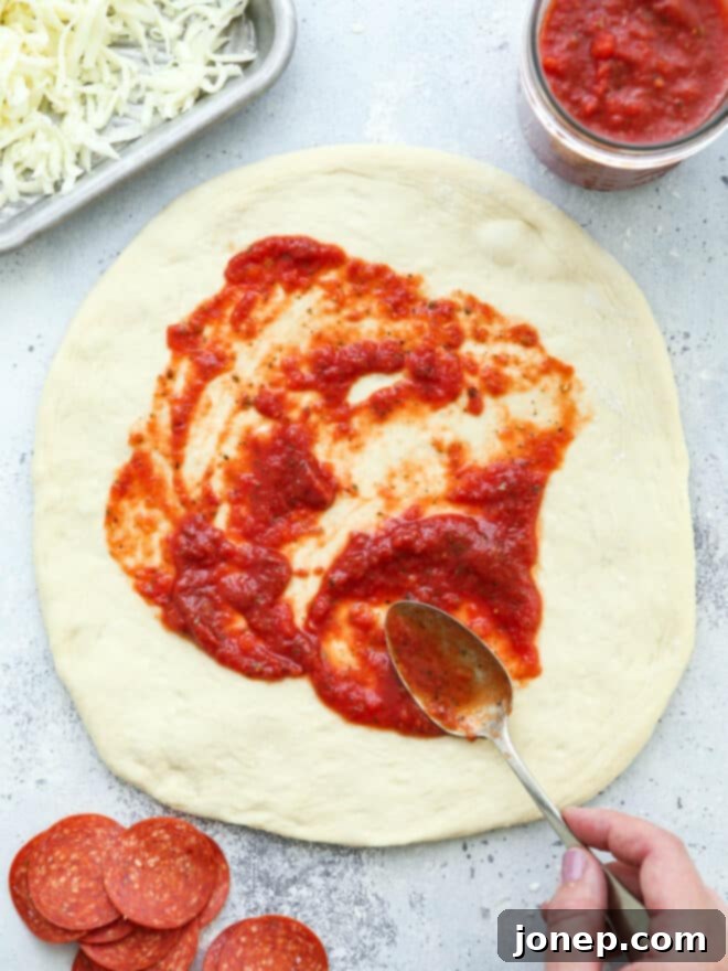 spreading pizza sauce on dough
