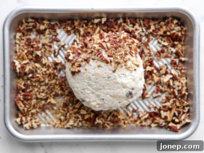 covering cheeseball with chopped pecans