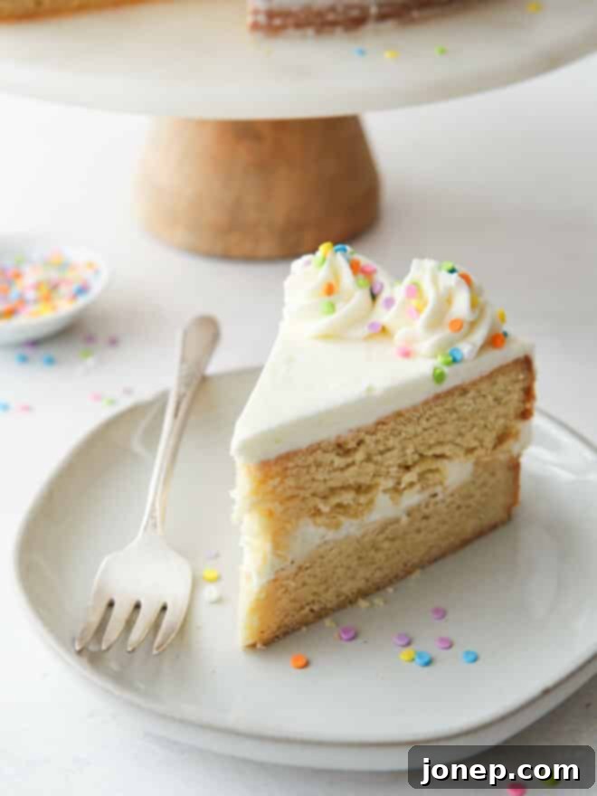 A close-up shot of a single slice of sugar cookie layer cake, revealing the distinct layers of cookie and frosting.