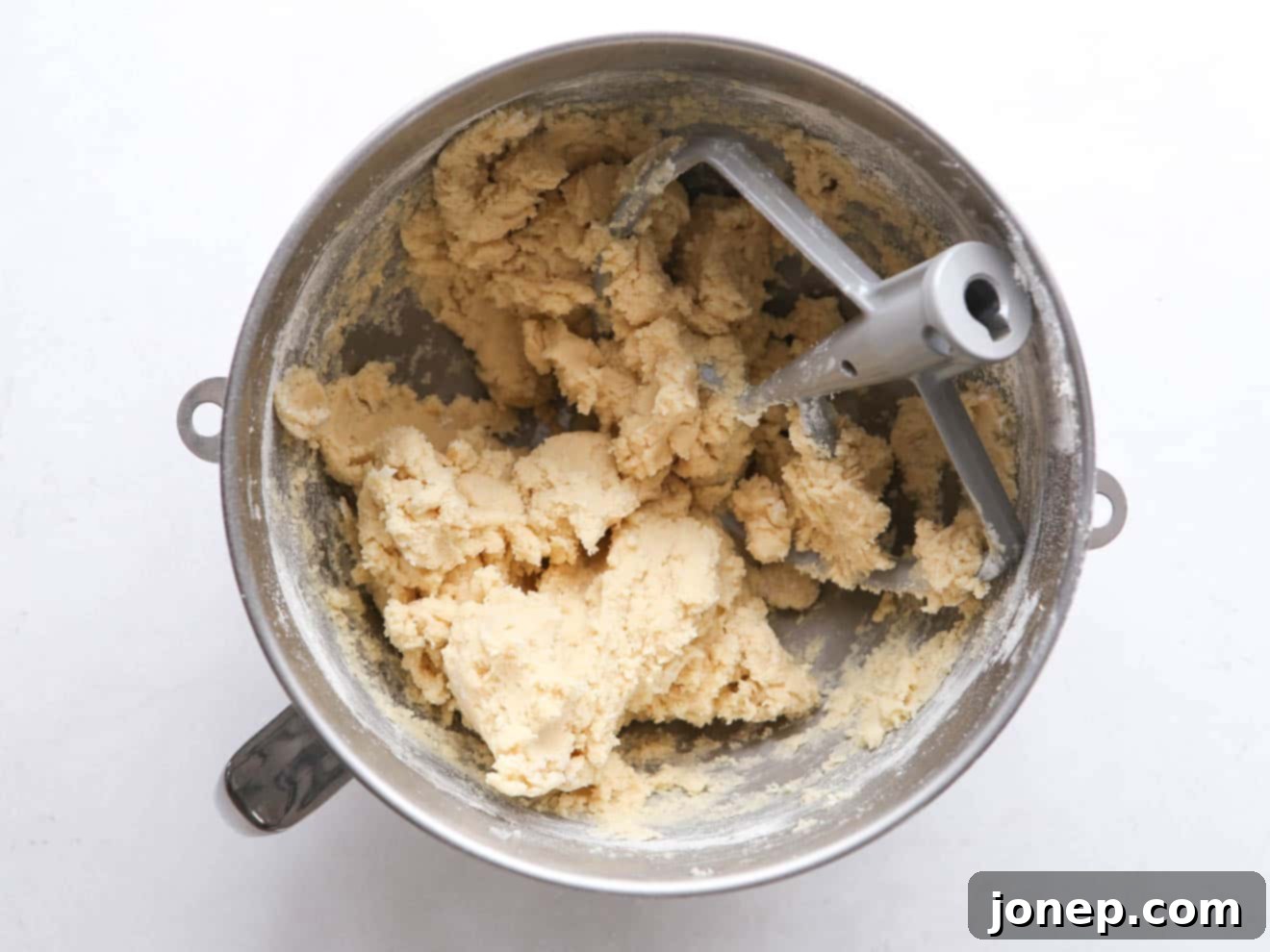 Close-up of fluffy sugar cookie dough in a stand mixer bowl, ready for baking.