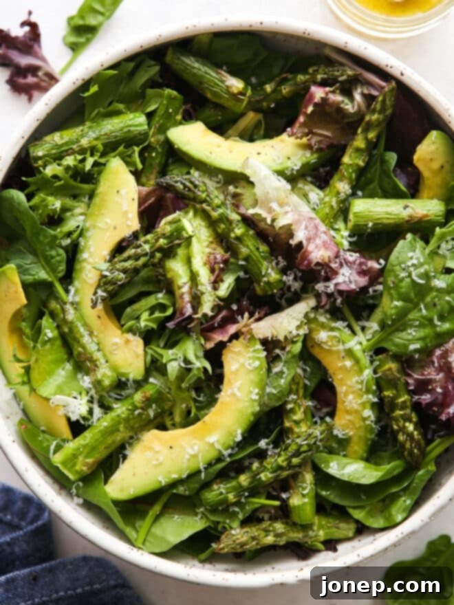 Roasted Asparagus and Creamy Avocado Medley 7 Close-up view of the perfectly tossed roasted asparagus avocado salad in a bowl, highlighting the varied textures and vibrant green, yellow, and white colors