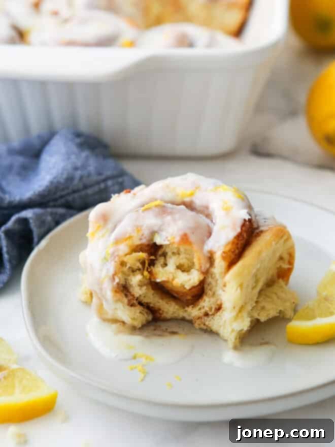 Zesty Lemon Cinnamon Rolls 3 Close-up of a lemon cinnamon roll with a bite taken, revealing its soft, gooey, cinnamon-swirled interior.