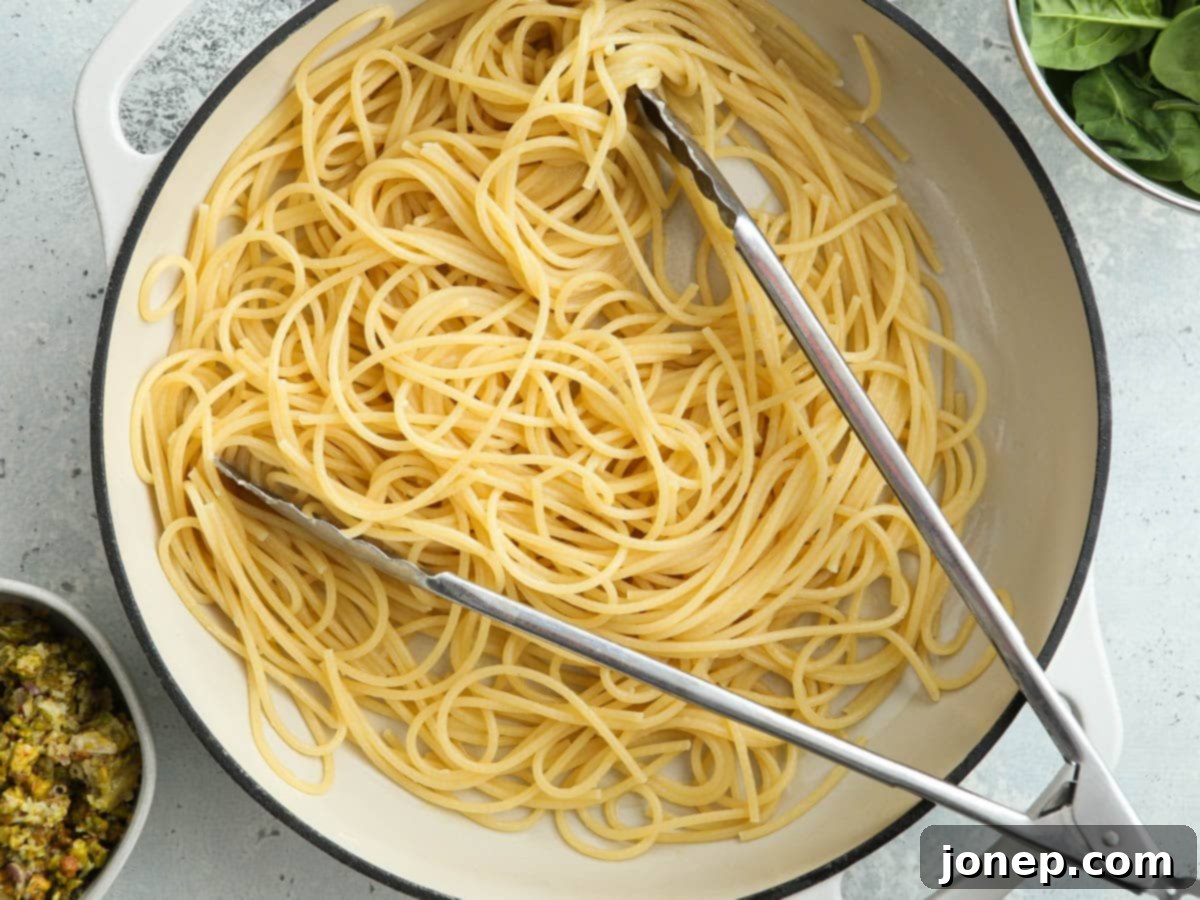 boiled pasta in pan ready to add spinach and lemon pistachio pesto