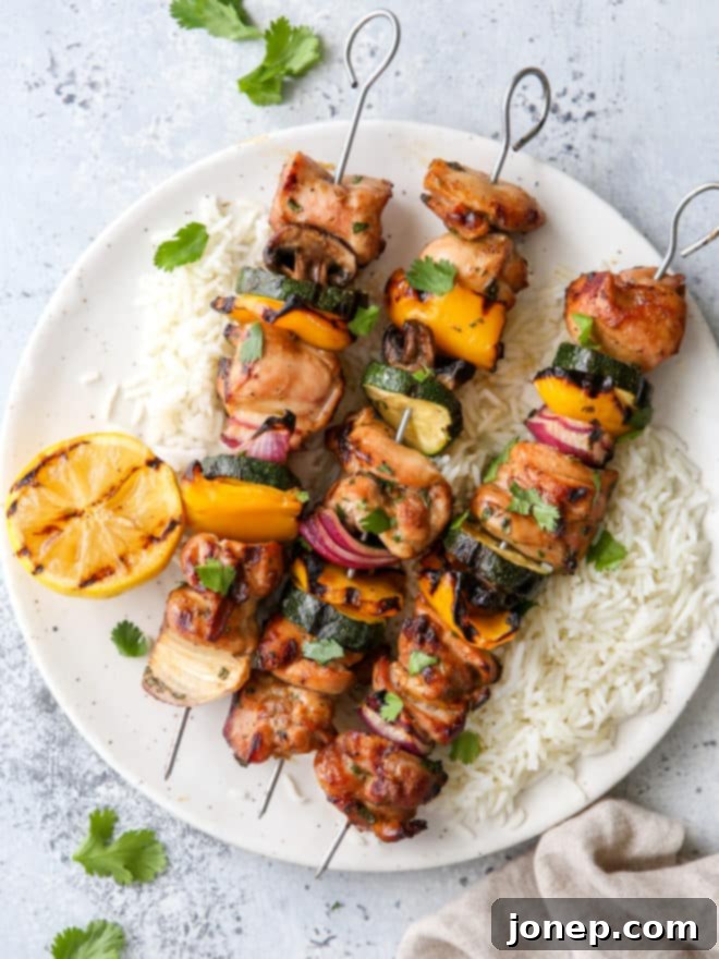 grilled lemon-cilantro veggie skewers on a plate with rice underneath
