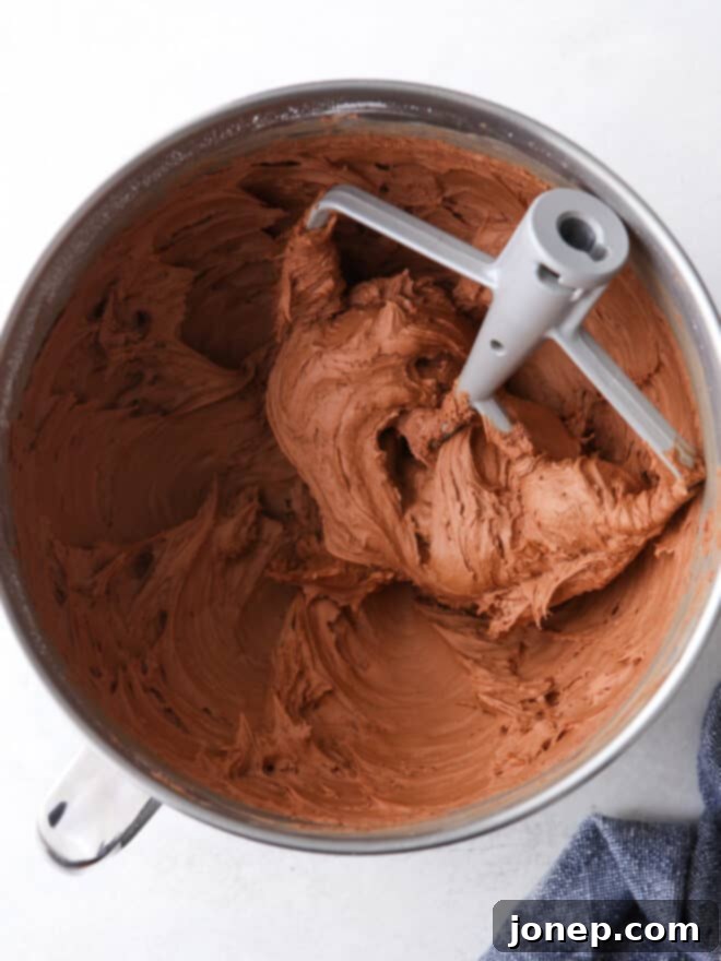 Decadent Chocolate Fudge Layer Cake 6 Easy fudge buttercream frosting in a mixing bowl, showing its creamy texture.