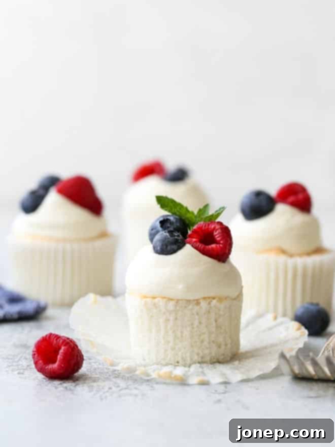 angel food cupcakes with whipped cream and fruit, one with wrapper turned down