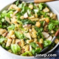 Chicken Caesar Pasta Bowl 10 Chicken Caesar Pasta Salad in a bowl with salad tongs, a perfect summer dish.