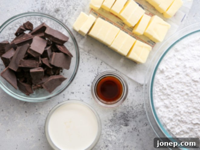 Effortless Decadent Fudge Buttercream 3 Key ingredients including unsweetened chocolate, powdered sugar, butter, and milk, laid out for easy fudge buttercream frosting preparation