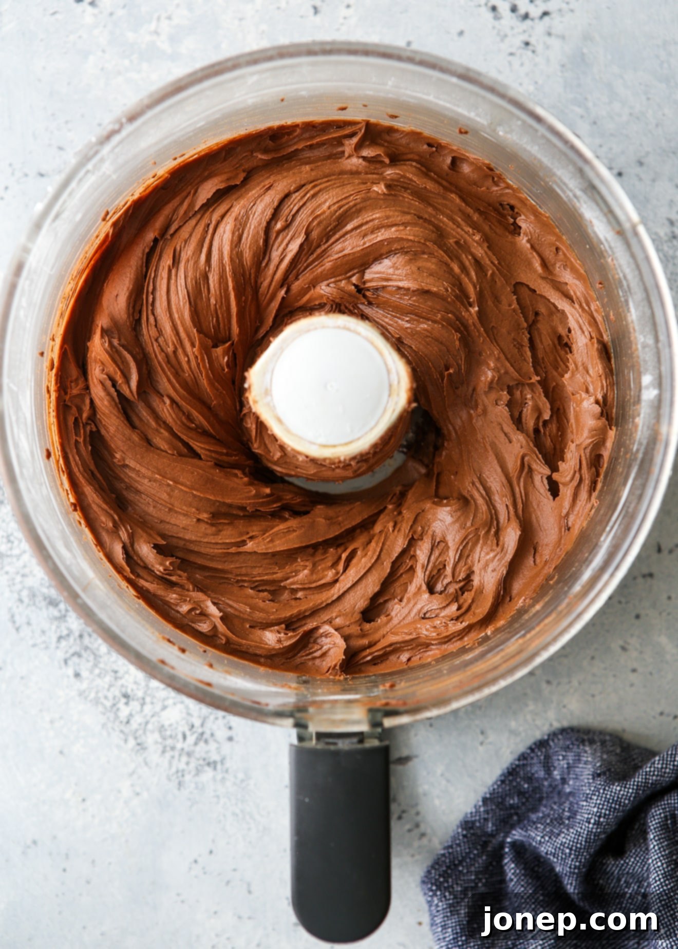 The smooth and creamy easy fudge buttercream frosting after being perfectly blended in the food processor, ready to use