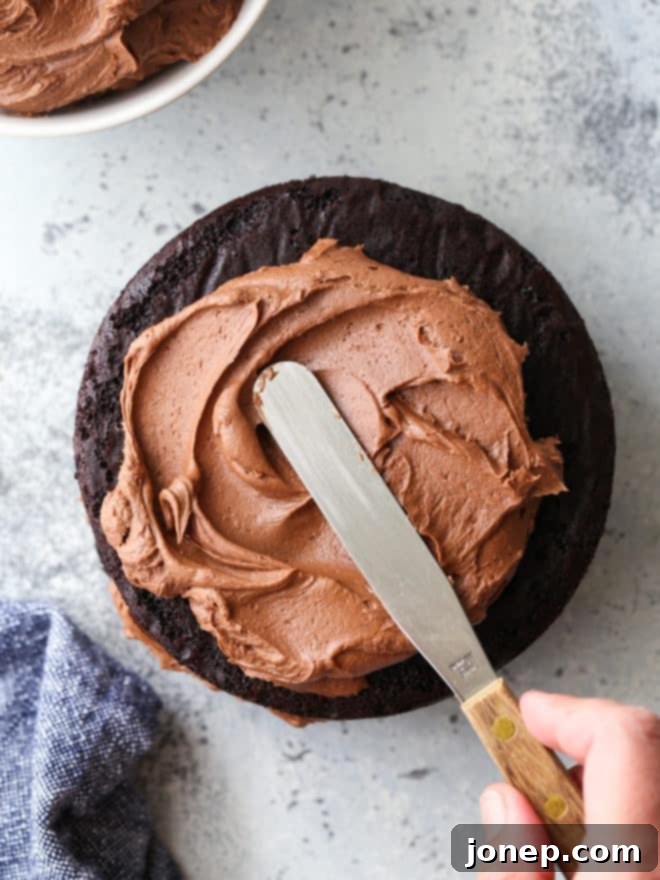 spreading easy fudge buttercream on a chocolate cake