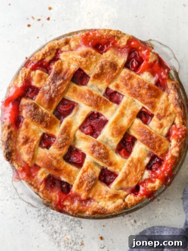A vibrant fruit pie beautifully topped with a golden, woven lattice pie crust, showcasing the intricate crisscross pattern before serving.