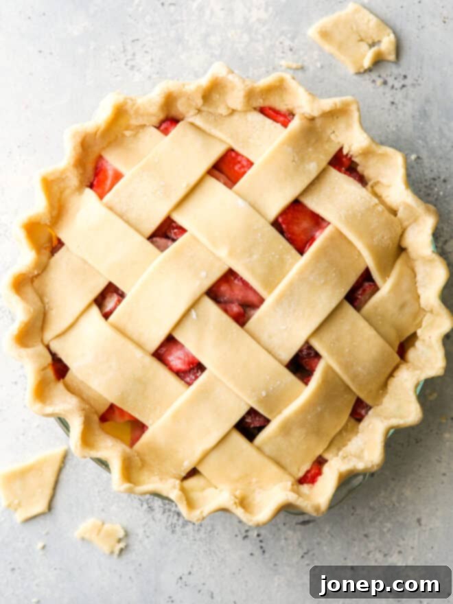 A beautifully prepared fruit pie, topped with a meticulously woven lattice crust and brushed with egg wash, poised for baking.