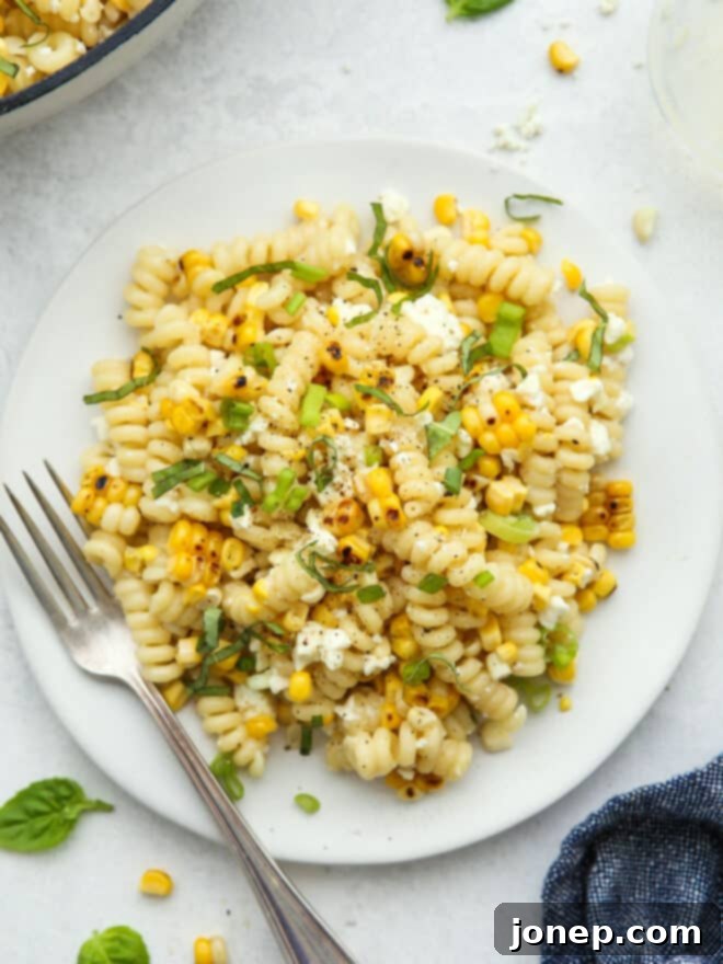 Smoky Creamy Grilled Corn Pasta 2 Closeup of a plate of creamy grilled corn pasta garnished with fresh basil leaves and crumbled feta