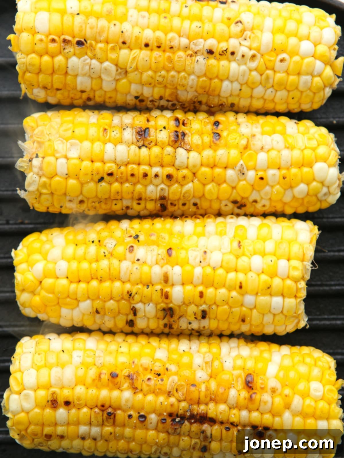 Smoky Creamy Grilled Corn Pasta 5 Close-up of ears of corn being grilled on an outdoor barbecue, showing beautiful char marks