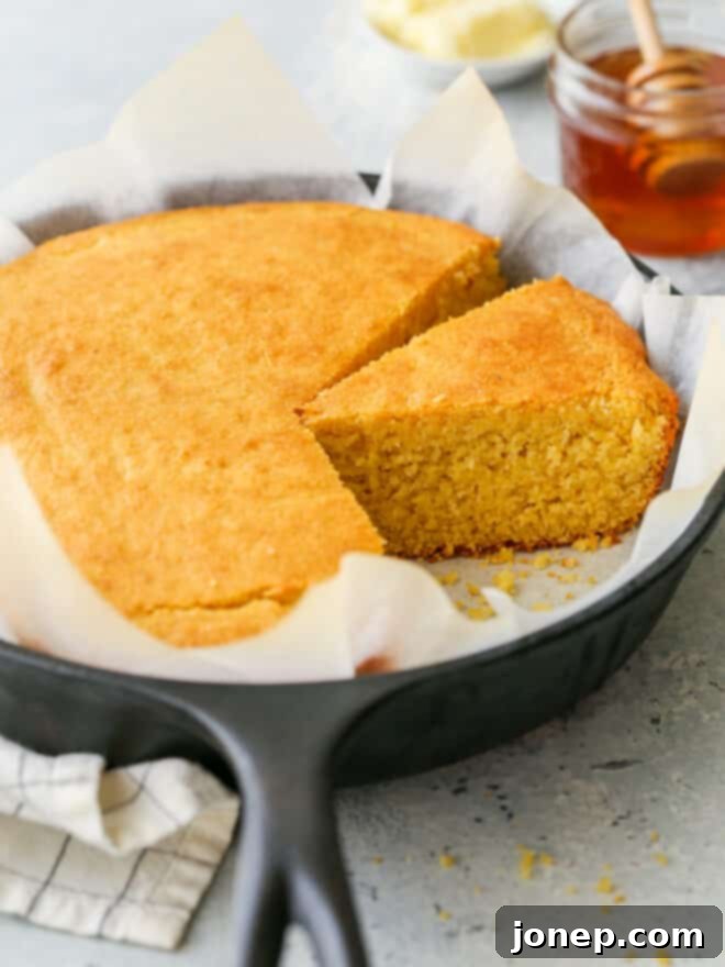 Honey-Kissed Buttermilk Cornbread 2 Closeup of sliced honey buttermilk cornbread in a cast iron skillet, showing its golden brown crust and tender crumb