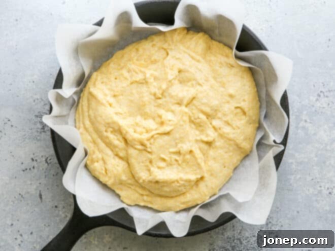 Honey buttermilk cornbread batter poured into a cast iron skillet, ready for baking