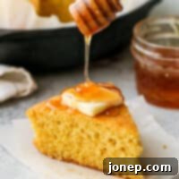 Honey-Kissed Buttermilk Cornbread 8 A slice of honey cornbread with honey being drizzled on top, ready to be enjoyed