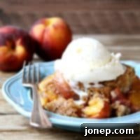 Effortless Slow Cooker Peach Cobbler 2 A small image of warm Slow Cooker Peach Cobbler with a dollop of whipped cream.