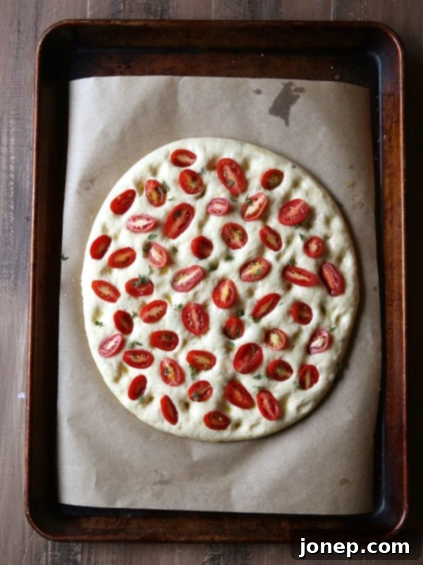 Close-up of focaccia dough being dimpled with fingers | completelydelicious.com